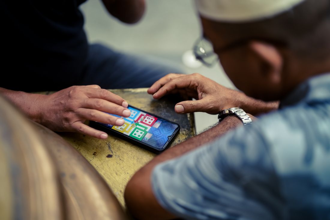 Dua orang bermain game di ponsel sambil bersantai